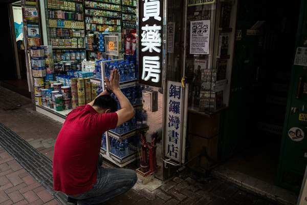 一名药房员工在铜锣湾书店入口旁拜神