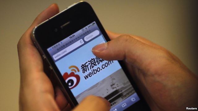 A man holds an iPhone as he visits the Sina Weibo microblogging site