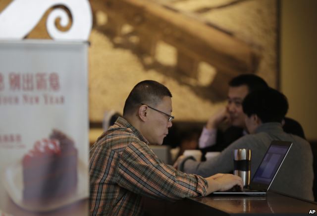 A man surfs Internet on his laptop computer at a Starbucks cafe in Beijing