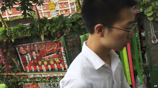 A man walks past a tricycle cart decorated with flowers and a poster with Chinese President Xi Jinping and other top leaders