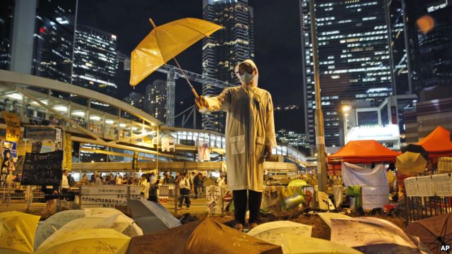 A protester holds an umbrella during a performance on a main road in the occupied areas outside government headquarters in Hong Kong's Admiralty in Hong Kong, Oct. 9, 2014