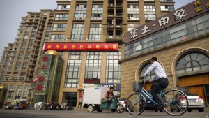 A delivery cart and cyclist ride past a building housing the Fengrui law firm in Beijing