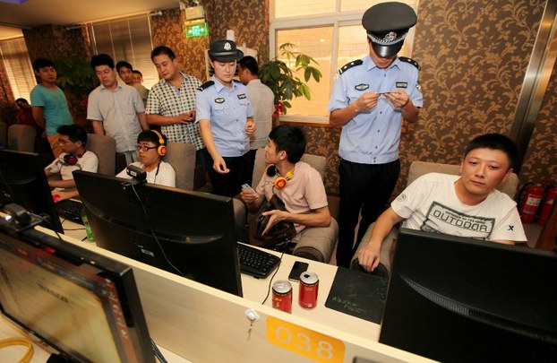 Police check the ID cards of netizens at an Internet cafe in Shandong province