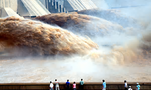 Tourists watch floodwaters gushing out of the Xiaolangdi dam during a sand-washing operation of the Yellow river in Jiyuan