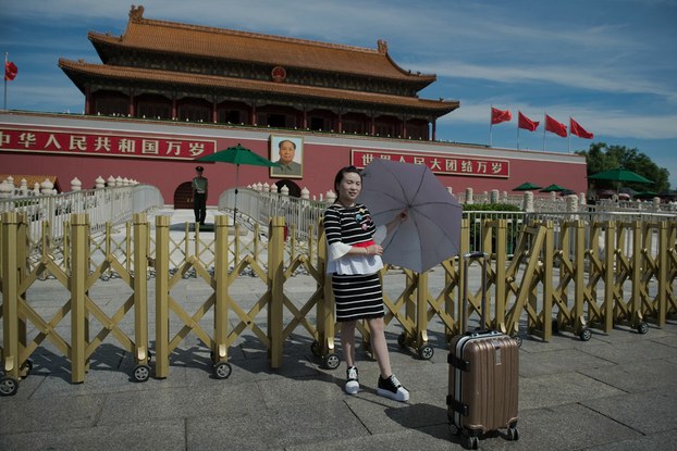 a-woman-stands-in-front-of-a-giant-portrait-of-mao-zedong-at-the-gate-of-the-forbidden-city-in-beijing-on-sept-9
