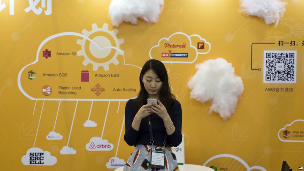 a-woman-uses-her-smartphone-near-a-booth-promoting-cloud-services-during-the-global-mobile-internet-conference-in-beijing
