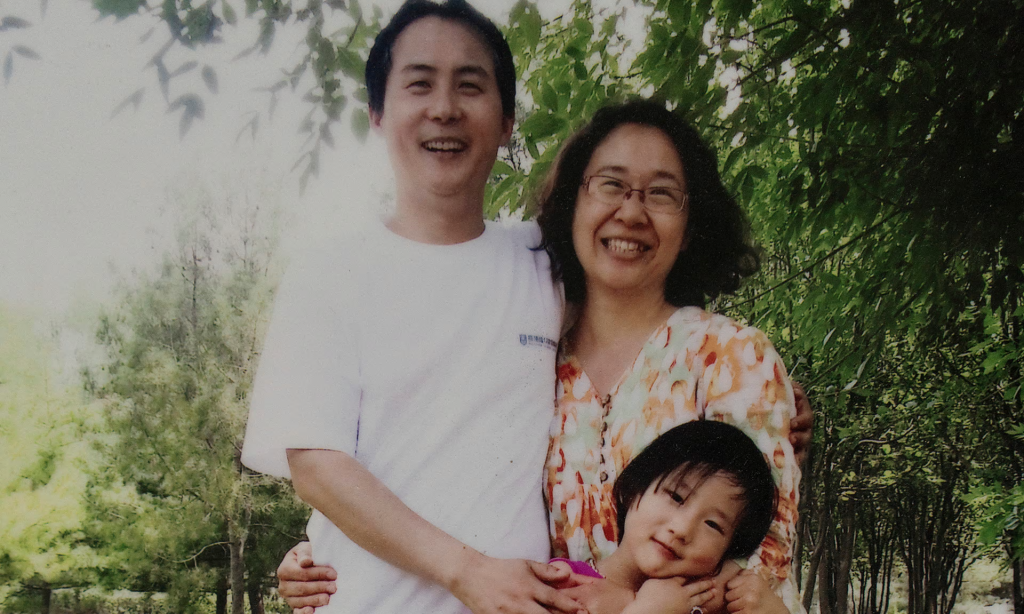 A photo of a printed family photo of Li Jiamei-her father and imprisoned lawyer Li Heping and her mother Wang Qiaoling at home in Beijing