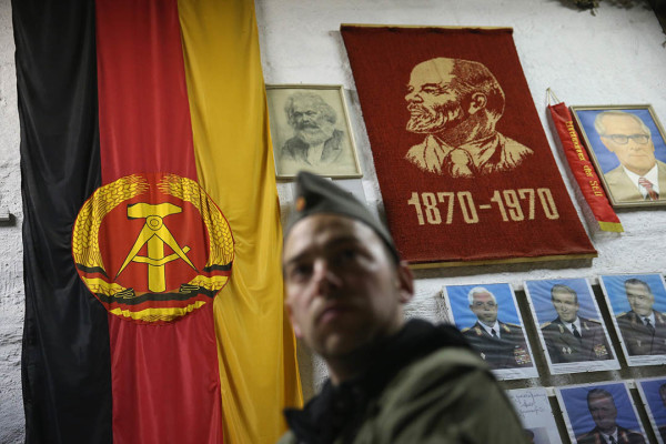 SUHL, GERMANY - OCTOBER 17: A visitor dressed as an East German NVA army soldier looks at memorabilia of the former communist East Germany (DDR), including the East German flag and portraits of Karl Marx, Vladimir Lenin and Erich Honecker, during an overnight stay in the Bunkermuseum Frauenwald on October 17, 2014 near Suhl, Germany. The bunker was built by the East German secret police (Ministry for State Security, or Ministerium fuer Staatssicherheit, also called the Stasi) in the 1970s and was one of at least 15 similar bunkers meant to serve as command and administrative centers in case of war. The bunker could house up to 130 people in its 3600 square meter facility, which had supplies for three weeks and decontamination systems against chemical attack. Today the bunker is a private museum that offers tours and overnight stays in which visitors are given the option of dressing as East German army soldiers for a more authentic experience. Germany is commemorating the 25th anniversary of the fall of the Berlin Wall, which signalled the collapse of communist East Germany (also called the DDR, or Deutsche Demokratische Republik) in 1989, in November of this year. (Photo by Sean Gallup/Getty Images)