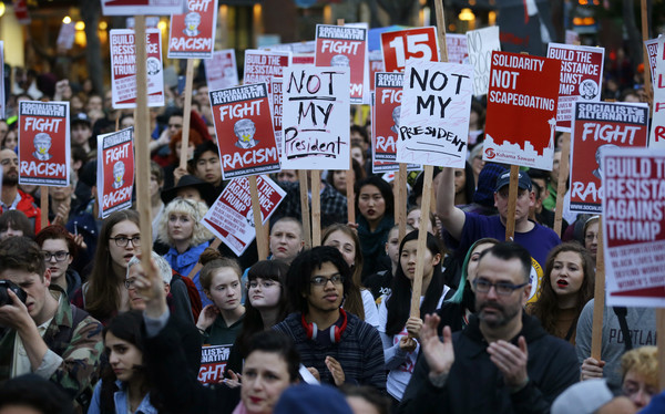 Protesters hold signs during a protest against the election of President-elect Donald Trump, Wednesday, Nov. 9, 2016, in downtown Seattle. (AP Photo/Ted S. Warren)