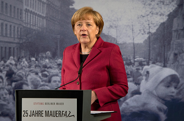 German Chancellor Angela Merkel delivers her speech in front of a giant reproduction of a photo dated from November 1989 as she opens an exhibition dedicated to the Berlin Wall during commemorations to mark the 25th anniversary of the fall of the Berlin Wall at the Berlin Wall Memorial in the Bernauer Strasse in Berlin, on November 9, 2014.   AFP PHOTO / DPA / SOEREN STACHE