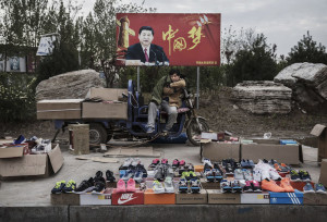 SHIJIAZHUANG, CHINA - APRIL 9: A Chinese vendor sells sneakers and shoes in the street in front of a sign showing Chinese President Xi Jinping with "China Dream" written on it, on April 9, 2017 in Shijiazhuang, Hebei province, China. China's economy grew 6.9 percent in the first quarter of 2017, a government report said on April 17, 2017, which was higher then expected and another signal that the world's second largest economy could be stabilizing. (Photo by Kevin Frayer/Getty Images)